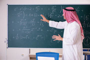 Arab teacher in front of chalkboard 