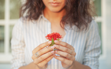 Young beautiful sensual woman with nice manicure holding the person red tropical flowers, natural...