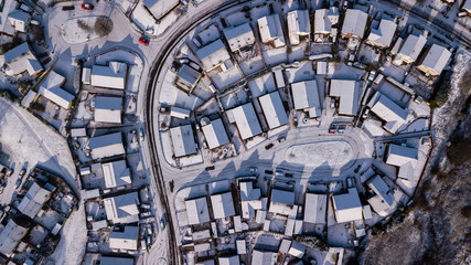 Aerial drone view of winding residential roads surrounded by fresh snowfall