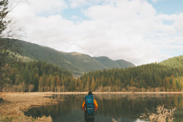 A hiking woman looking out at a beautiful view of mountains and a calm lake. 