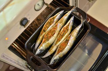 Close up of baking tray with fish in the oven.