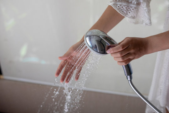 Close-up of a woman's hand checking water condition in the shower