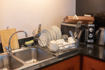 Different clean dishes in dish drying rack on kitchen counter