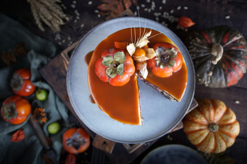 Autumn cake with persimmon and caramel with a pumpkin and a girl in a burgundy dress on a black background, Atmospheric dark food photos, Pastry Homemade in Womans hands, Selective focus