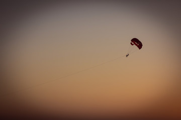 Three People are flying by the parachute behind the boat. Parasailing on Karon beach. Sunset. Phuket. Thailand