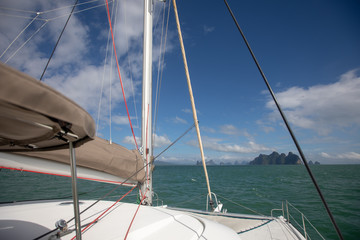View of the blue sea water from the side of a sailboat with rigging and sails. Tackle barge, sail, masts, yards, deck, ropes, cables