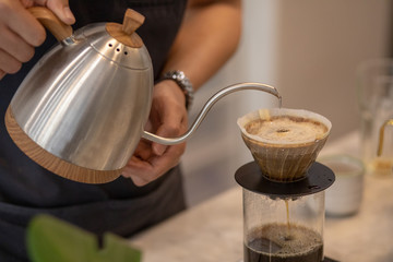 Barista Brewing Drip Coffee, Hand Pouring Hot Water from The Kettle over The Coffee Powder.  Close up