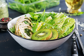 Buddha bowl dish with chicken fillet, avocado, cucumber, fresh arugula salad and sesame. Detox and healthy keto diet bowl concept. Overhead