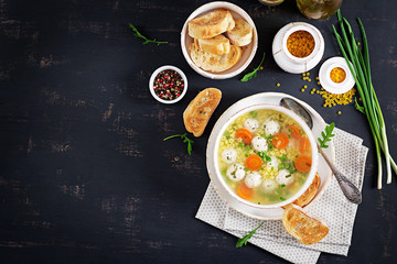 Italian meatball soup and  Stelline  pasta in bowl on black table. Dietary soup. Baby menu. Tasty food. Top view. Copy Space