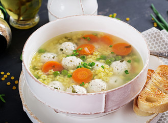 Italian meatball soup and  Stelline  pasta in bowl on black table. Dietary soup. Baby menu. Tasty food.