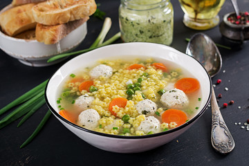 Italian meatball soup and  Stelline  gluten free pasta in bowl on black table. Dietary soup. Baby menu. Tasty food.