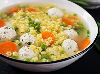 Italian meatball soup and  Stelline  gluten free pasta in bowl on black table. Dietary soup. Baby menu. Tasty food.