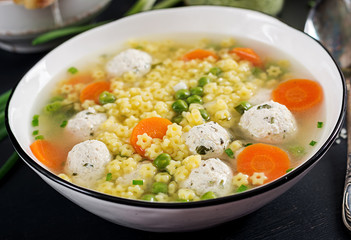 Italian meatball soup and  Stelline  gluten free pasta in bowl on black table. Dietary soup. Baby menu. Tasty food.