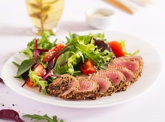 Japanese traditional salad with pieces of medium-rare grilled Ahi tuna and sesame with fresh vegetable salad on a plate. Authentic Japanese food.