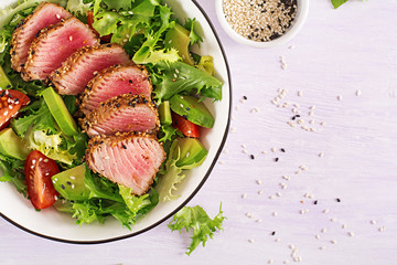 Tuna salad. Japanese traditional salad with pieces of medium-rare grilled Ahi tuna and sesame with fresh vegetable on a bowl. Authentic Japanese food. Top view