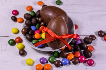 Chocolate easter eggs and multicolored candies on wooden table