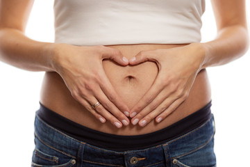 Body care, pregnancy diet concept, female hands forming a heart shape on the abdomen, isolated on...