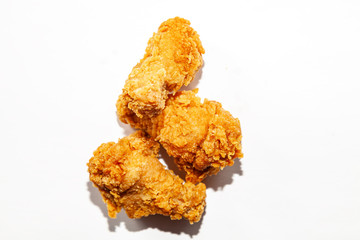 Fried mouth-watering three chicken wings in a spicy sauce and brown breaded lie in a handful isolated on a white background, unhealthy fatty fast food.