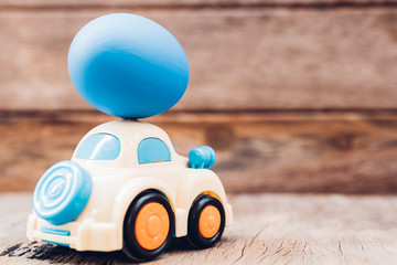 Easter egg and toy car on wooden background,