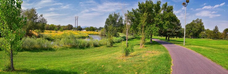 Views of Jordan River Trail with surrounding trees, Russian Olive, cottonwood and silt filled muddy water along the Wasatch Front Rocky Mountains, in Salt Lake City, Utah.
