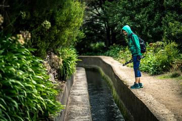 Portrait of young girl in green sweatshirt walking by levana on Madeira island, up in mountains. Hiking by the trail among green, tropical and old forests. Portugal.