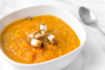 pumpkin soup with crackers, spoon on a white background,