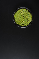 Guacamole spread. Mexican food guacamole in bowl on a black background.
