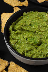 Guacamole with Nachos on black background. Mexican traditional food