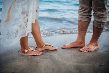 Fototapeta na wymiar Bride and groom Couple walking on the beach. Man and woman's Feet in the sand. Wedding at the beach
