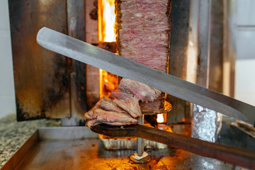 Turkish Doner Kebab, Shawarma or Gyros. Chef cutting with doner knife Traditional Turkish Doner...