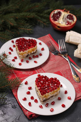 Festive salad in layers in the shape of a heart, decorated with pomegranate seeds on a dark background