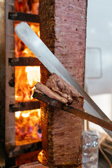 Turkish Doner Kebab, Shawarma or Gyros. Chef cutting with doner knife Traditional Turkish Doner Kebab meat, shawarma or gyros. Turkish, greek or middle eastern arab style doner kebab food spit.