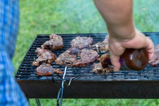 Man basting meat with barbecue sauce while grilling / barbeque