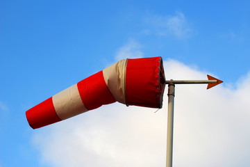 A red and white windsock with a weather vane