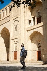 Young female traveler with backpack and with hat on the street. Travel concept. Uzbekistan, Bukhara