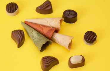 ice cream cones and chocolates on yellow background