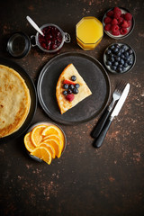 Tasety homemade pancake on black ceramic plate. Placed on dark rusty table. With fresh fruits, orange juice and marmalade. Top view, Flat lay.
