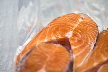 Lots of fresh raw salmon steaks on ice in supermarket. Fresh raw salmon on ice. Big pieces raw salmon. Fish on ice. Salmon on counter.