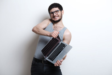 Screaming young guy opening laptop over white background. Wearing t-shirt and black jeans