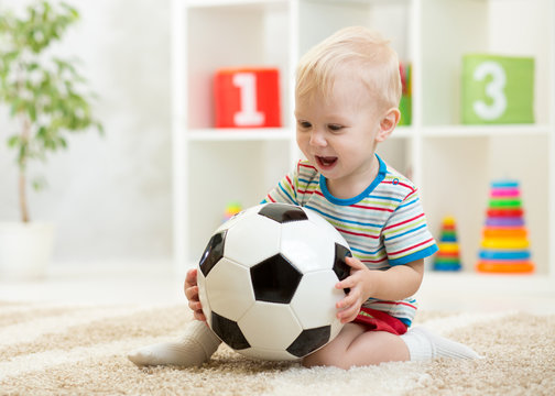 baby boy playing with ball in nursery or at home