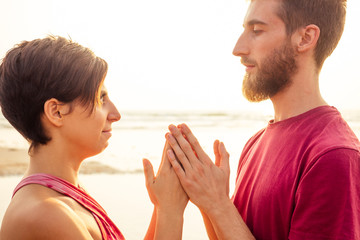 muladhara swadhisthana manipula tantra yoga on the beach man and woman meditates sitting on the sand by the sea at sunset romantic Valentine's Day.couple practicing yoga steam