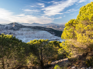limestone mine in the mountains, with trees in front and sunset light