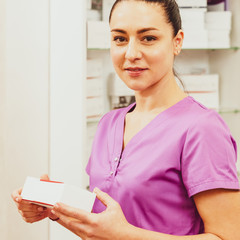 Portrait of happy professional cosmetologist holding box with medication for procedure