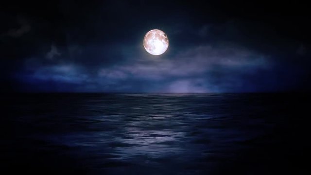 The bright moon shines over the sea horizon against the night sky and gloomy running clouds
