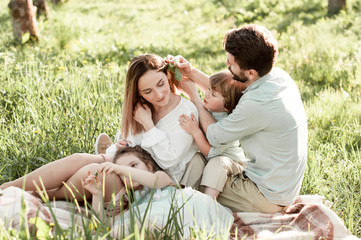 Happy family in a garden,  parents and their lovely daughter and son are lying on the grass
