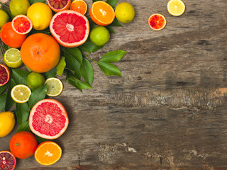 many different juicy and healthy citrus fruits lie together on an old, vintage wood background