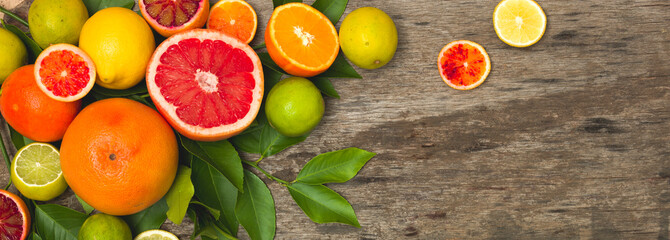 many different juicy and healthy citrus fruits lie together on an old, vintage wood background
