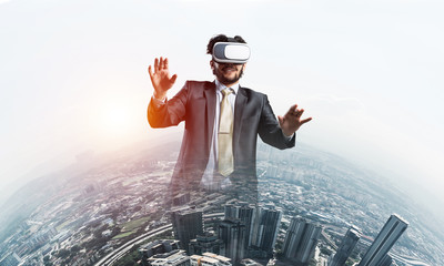 Handsome elegant businessman experiencing impressive virtual reality and business city at backdrop