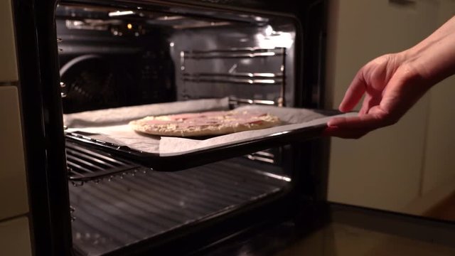 Putting in a frozen pizza in the owen for baking