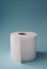 Roll of white toilet paper on a blue background, vertical image with copy space.
